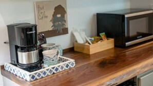 Eine Küchenzeile mit Kaffeemaschine, Tassen, einer Mikrowelle und einer Holzkiste mit Gegenständen.