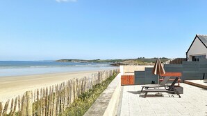Una propiedad frente a la playa con patio, sillas de descanso y vistas al océano.
