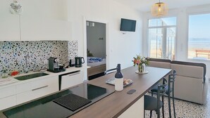 Una cocina moderna con una isla grande, un área de comedor con un sofá y un televisor montado en la pared.