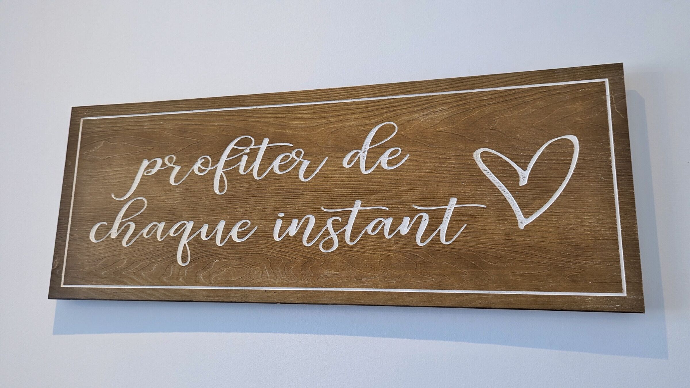 A wooden sign with the text "profiter de chaque instant" and a heart symbol.