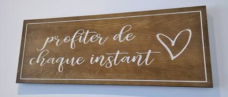 A wooden sign with the text "profiter de chaque instant" and a heart symbol.