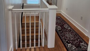 A staircase with white railings leading to a landing with a patterned rug and a door with blinds. - Great for working professionals: medical, construction, etc. LTE, or Mid-term! (Grand Rapids)
