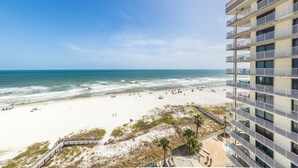 Un hotel frente a la playa con varios balcones, una playa de arena y vistas al océano.