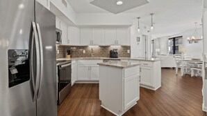 Una cocina moderna con armarios blancos, un refrigerador de acero inoxidable y una isla central.