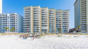 Un hotel sulla spiaggia con diversi edifici a grattacielo, una spiaggia sabbiosa e una passerella in legno che conduce all'ingresso.