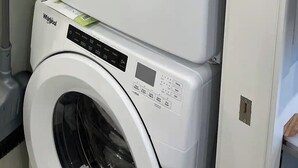 Una lavadora y secadora apiladas, con paneles de control y una manguera.