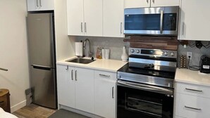 Una cocina moderna con armarios blancos, electrodomésticos de acero inoxidable y un microondas integrado.