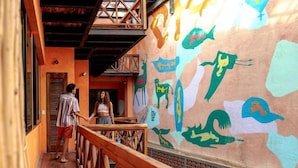 A corridor with a wooden railing, a wall with colorful animal murals, and a door at the end. - Casa Pepe Hostel Boutique - Sayulita (Sayulita)