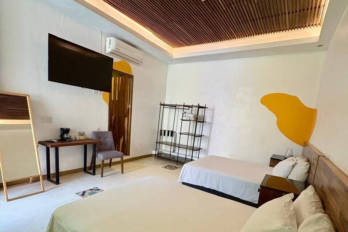 Quarto moderno com uma cama grande, uma escrivaninha, uma cadeira e uma TV fixada na parede.