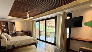 A spacious bedroom with a large bed, a sofa, a flat-screen TV, and a ceiling fan. - Casa Pepe Hostel Boutique - Sayulita (Sayulita)