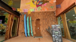 A restaurant entrance with a wooden floor, a pineapple mural, and surfboards against the wall. - Casa Pepe Hostel Boutique - Sayulita (Sayulita)