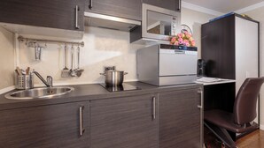 A modern kitchen with dark wood cabinets, a stainless steel sink, and a built-in microwave. - Studio with Balcony, Business Studio, 1 Twin Bed  (LUXEMBOURG)