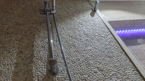 A shower with a handheld showerhead and a handheld shower attachment on a pebble-textured floor. - Studio with Balcony, Business Studio, 1 Twin Bed  (LUXEMBOURG)