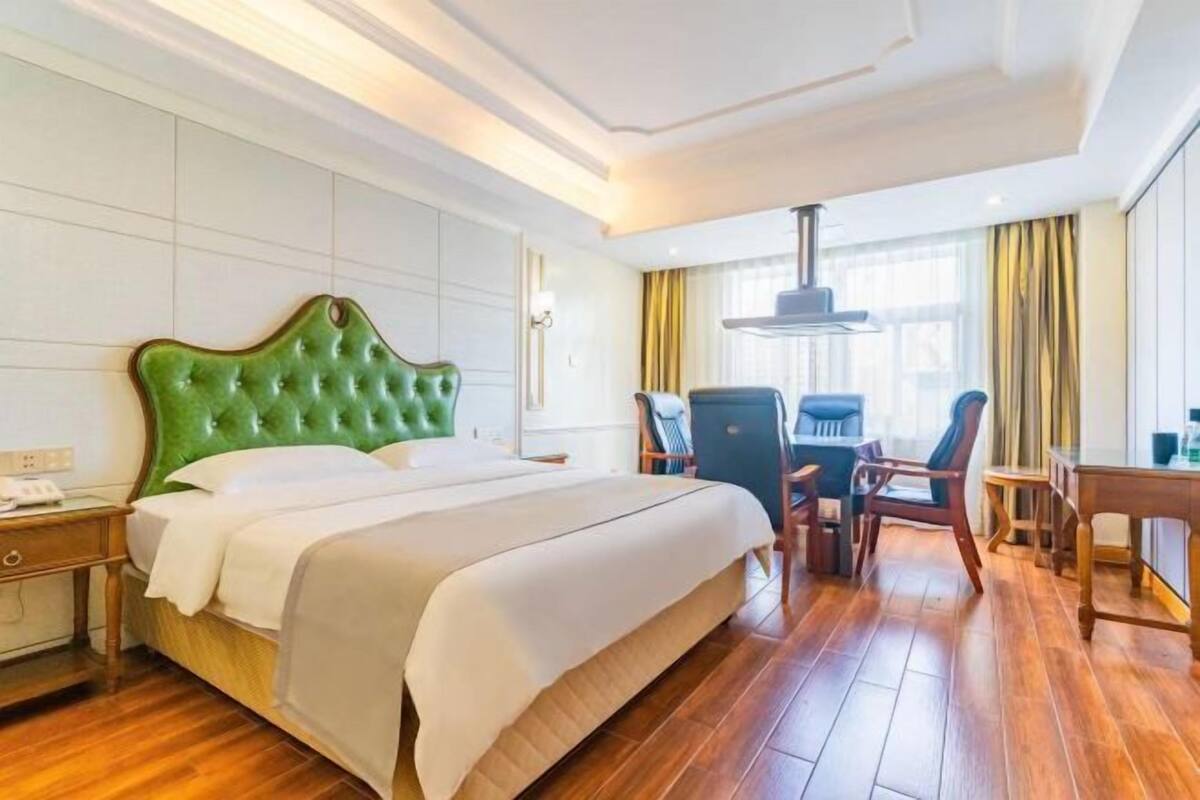 Una habitación de hotel con una cama grande, un escritorio, una silla y una ventana con cortinas.