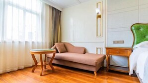 A hotel room with a sofa, a small round table, a nightstand, and a bed.