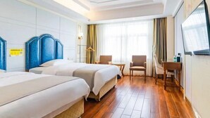 A hotel room with two beds, a TV, a small table, and a chair.