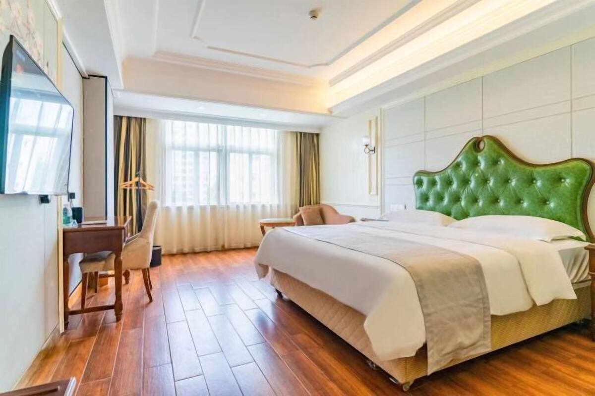 Una habitación de hotel con una cama grande, un escritorio, una silla y un televisor.