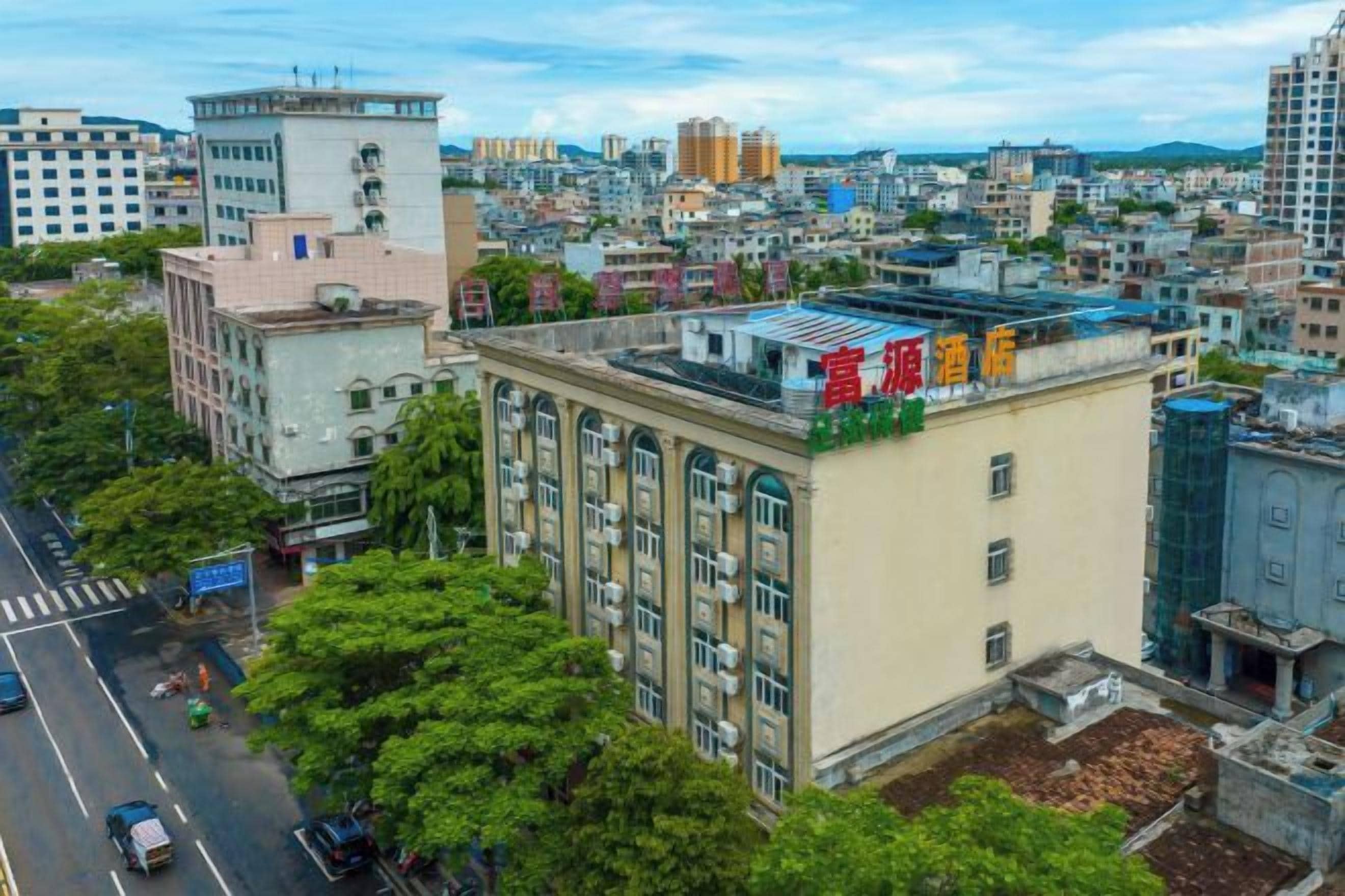 A multi-story building with a flat roof, surrounded by other buildings and trees.