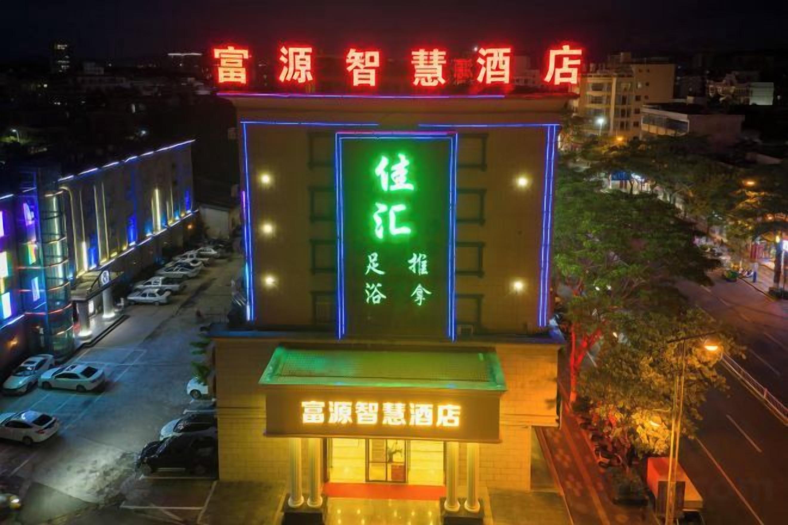 A hotel with a prominent neon sign, a visible entrance, and a parking lot.