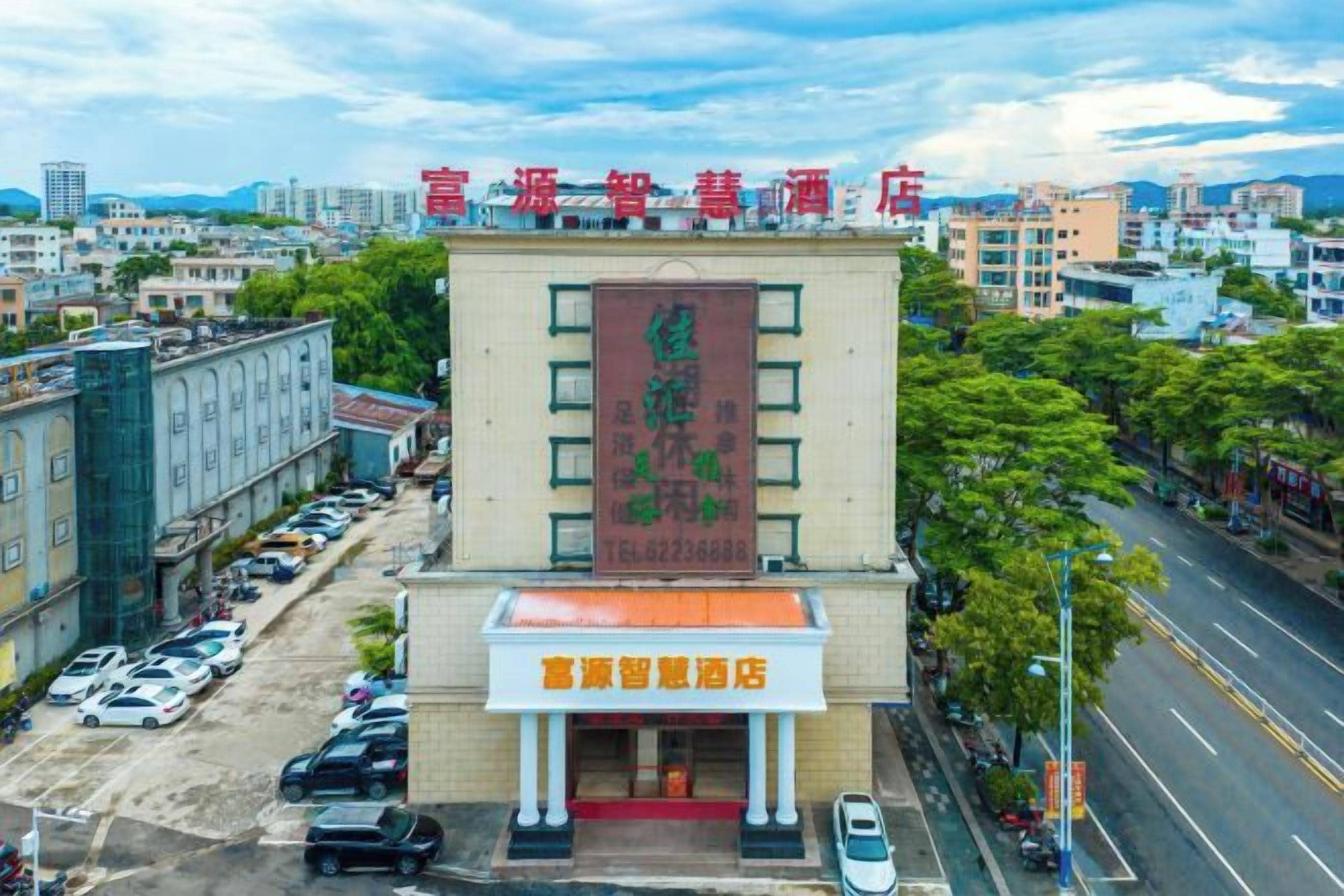 A hotel with a prominent sign, a parking lot, and a street view.
