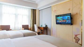 A hotel room with two beds, a desk, and a TV mounted on the wall displaying various channels.