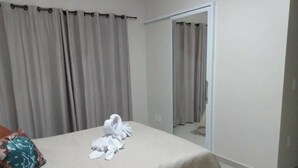 Una camera d'albergo con un letto, un cuscino floreale e un asciugamano sul letto.