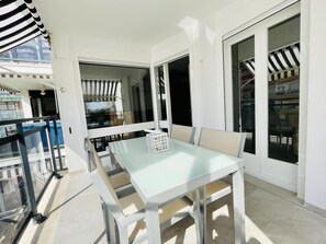 Un balcon avec une table et des chaises en verre, une piscine et une vue sur les environs.