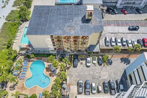 An aerial view of a hotel with a swimming pool, multiple balconies, and a parking lot. - Pool Access: Oceanfront Myrtle Beach Getaway! (Myrtle Beach)