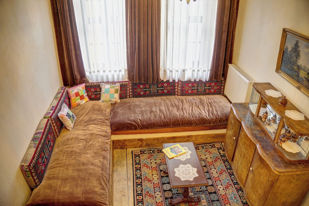 A cozy living room with a sofa, patterned cushions, a small table, and a decorative cabinet.