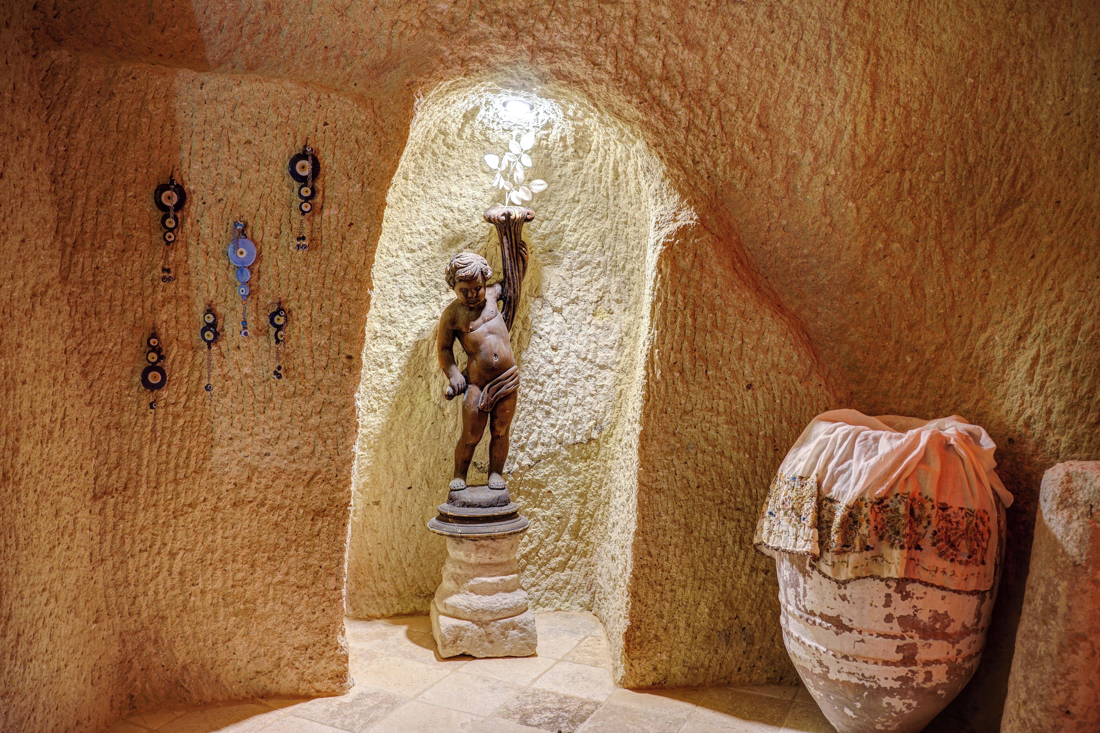 A statue in a niche with a tiled floor and a stone wall.