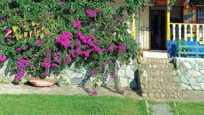 Ein Gebäude mit rotem Ziegeldach, einer Steinmauer und einem Garten mit rosa Blüten.