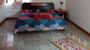 Ein Schlafzimmer mit einem Bett, einem Nachttisch und einem Fenster mit roten Vorhängen.