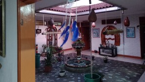 Ein Innenhof mit Brunnen, hängenden Dekorationen und Kübelpflanzen.