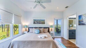 Une chambre à coucher avec un lit, un ventilateur de plafond, des œuvres d’art et une vue sur l’extérieur.