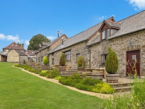 A row of stone buildings with a well-maintained lawn and potted plants.