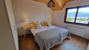 A bedroom with a bed, two bedside tables, a window, and a radiator. - Preciosa Villa de 5 dormitorios Rias Bajas (Arcade)