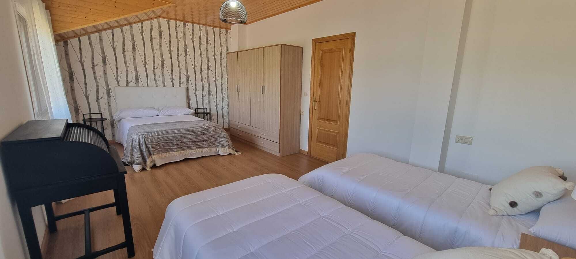 A bedroom with two beds, a desk, and a wardrobe.
