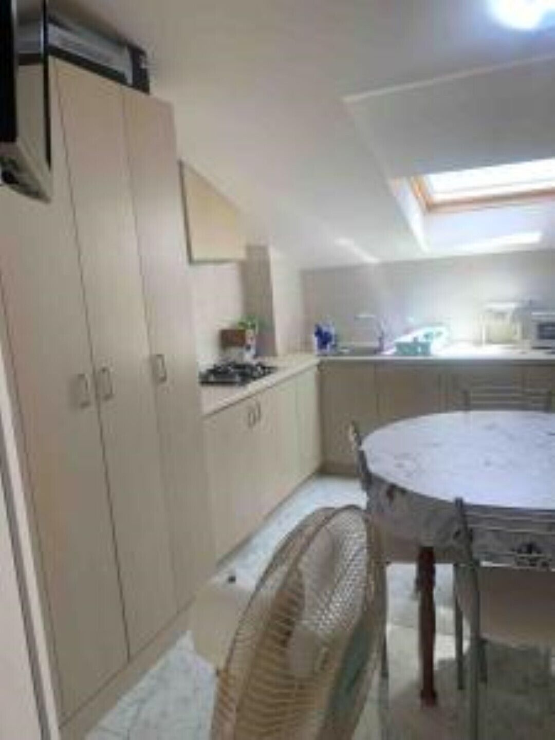 A compact kitchen with a dining table, a fan, and cabinets.