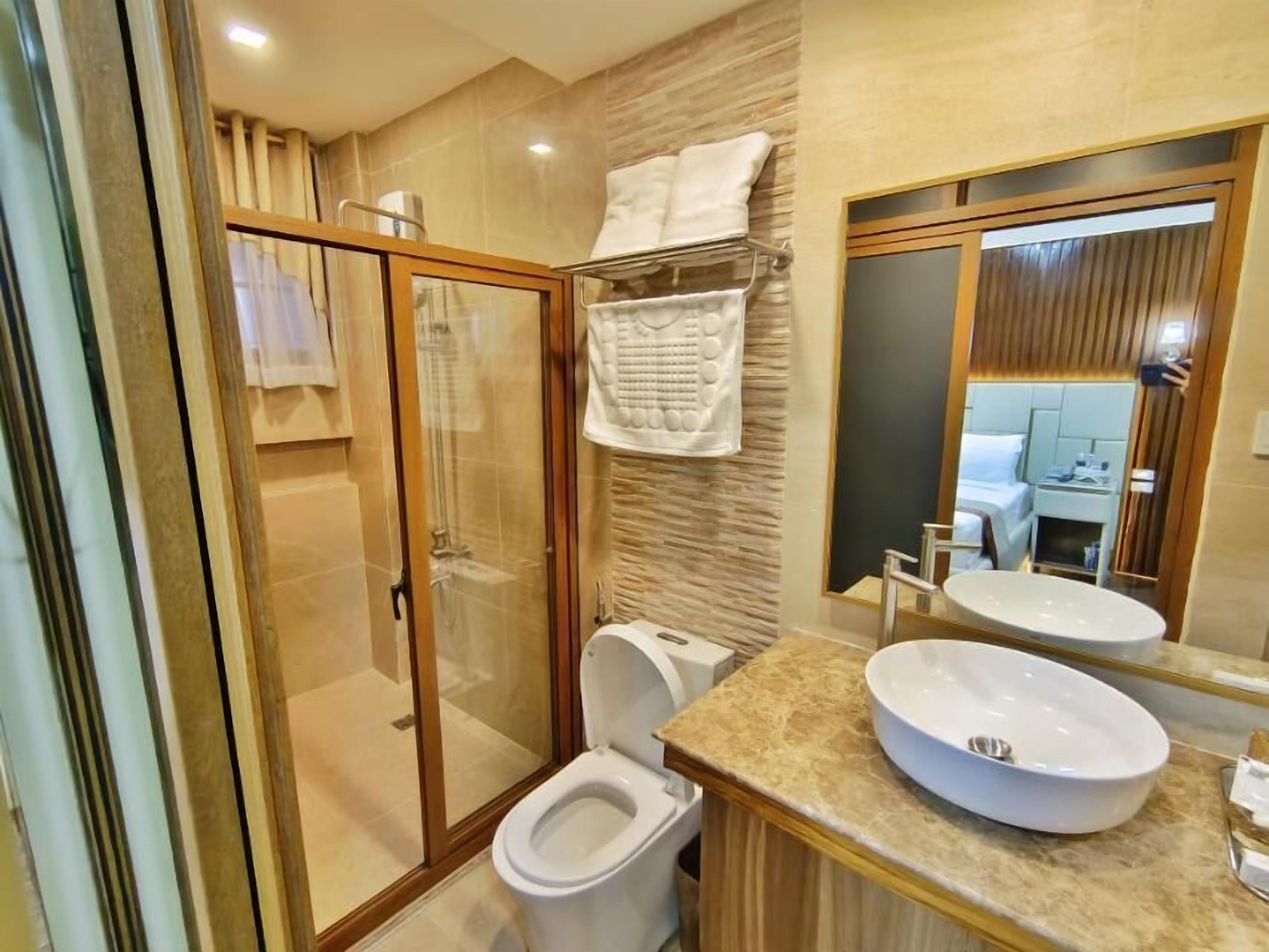 A modern bathroom with a glass-enclosed shower, a toilet, a sink, and a large mirror.