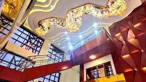 Ein mehrgeschossiges Interieur mit moderner Treppe, Glasgeländern und einer dekorativen Decke.