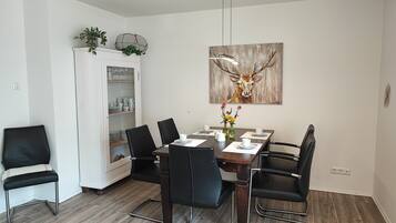 A dining area with a wooden table, black chairs, a cabinet with dishes, and a deer painting on the wall.