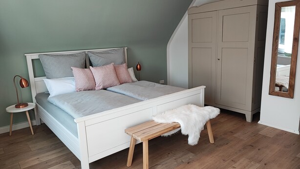 Une chambre à coucher comprenant un lit, une table de chevet, une lampe, une armoire et un miroir.