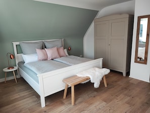 Une chambre à coucher comprenant un lit, une table de chevet, une lampe, une armoire et un miroir.
