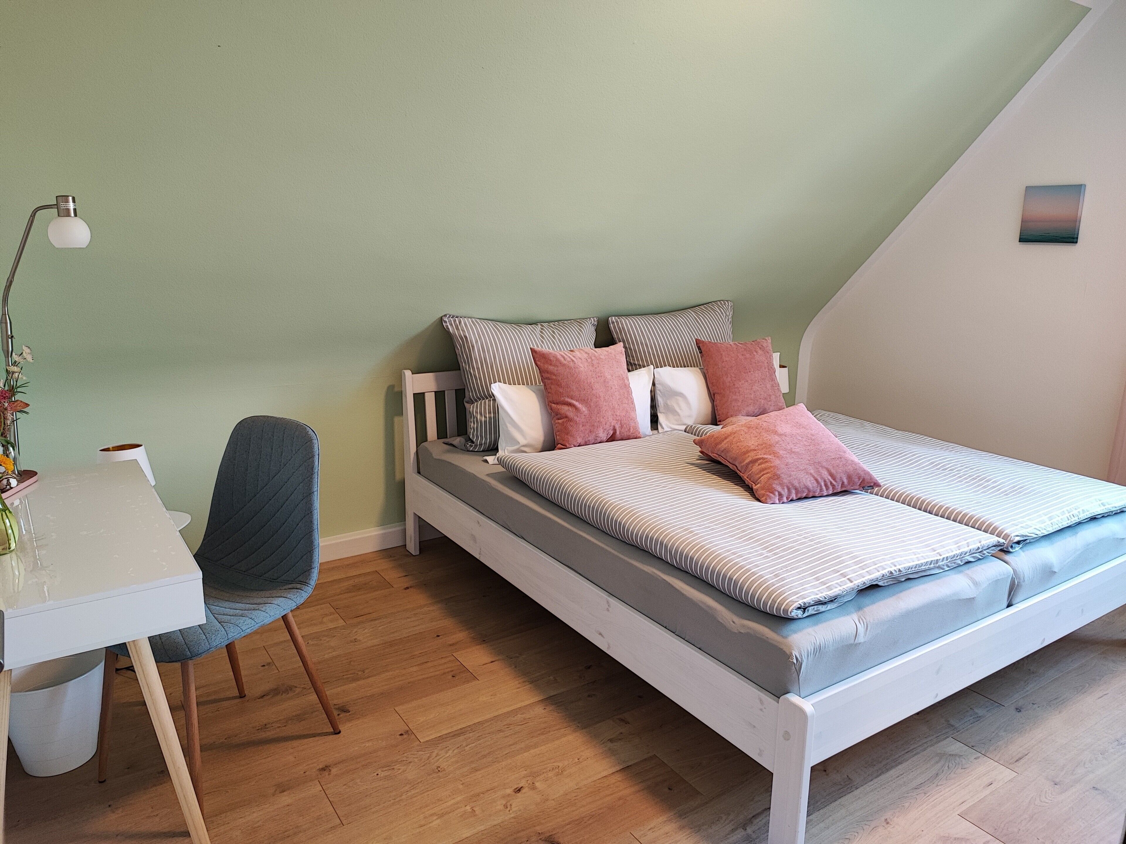 A bedroom with a bed, a desk, and a chair.