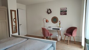 Une chambre à coucher comprenant un lit, un bureau, deux chaises et une commode.