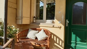 A wooden bench with cushions, a small table, and a green door.