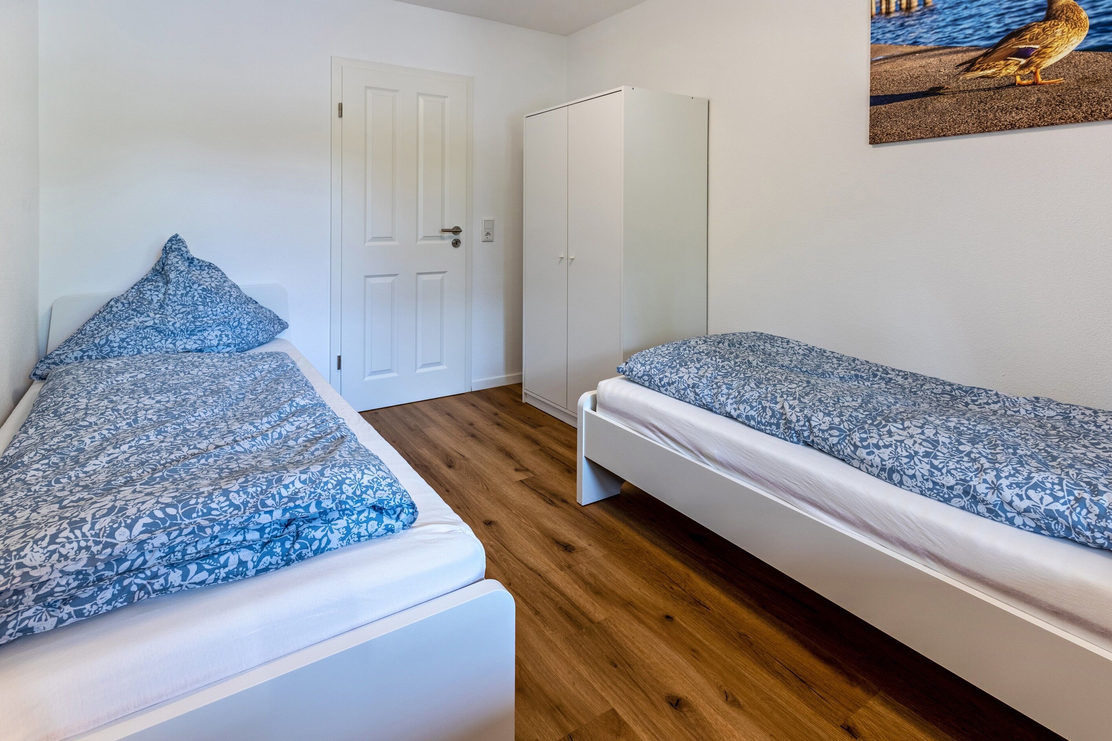 A room with two beds, a wardrobe, and a door.