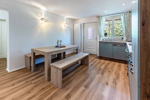 A modern kitchen with a wooden bench, built-in appliances, and a window with curtains.