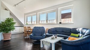 Una sala moderna con un sofá modular, un comedor y ventanas amplias.