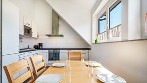 Una cocina moderna con armarios blancos, una mesa de comedor con platos, vasos y cubiertos, y un ventanal con vistas.